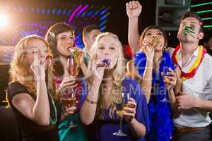 Group of friends blowing party horn in bar