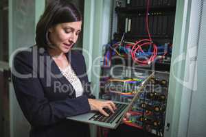 Technician using laptop while analyzing server