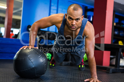 Serious man doing push-ups with exercise ball