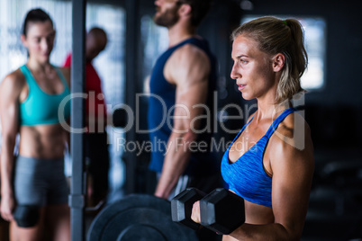 Thoughtful woman lifting dumbbell in gym