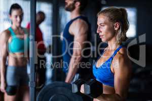 Thoughtful woman lifting dumbbell in gym