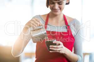 Waitress making cup of coffee at counter in cafe