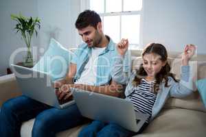 Father and daughter using laptop in the living room