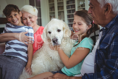Grandparents and grandchildren sitting on sofa with pet dog
