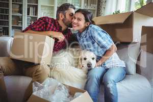 Man kissing woman while unpacking carton boxes