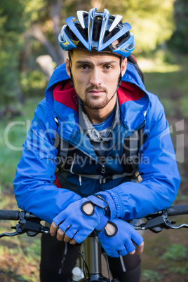 Portrait of male mountain biker with bicycle in the forest