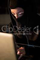 Woman in balaclava using laptop