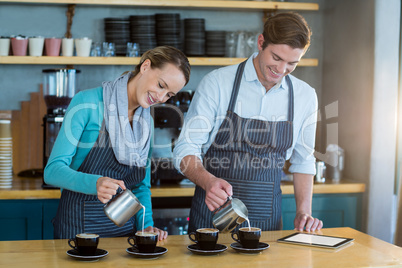 Waiter and waitress making cup of coffee at counter in cafe