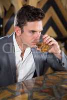 Depressed man having glass of whisky at counter