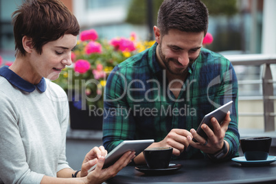 Businesspeople using digital tablet while having coffee