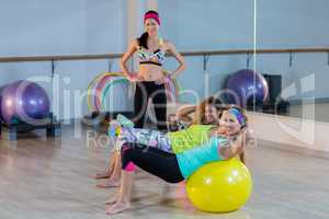 Women exercising on exercise ball with female trainer