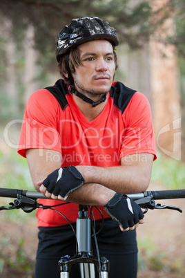 Male mountain biker with bicycle in the forest