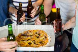Group of friends having bottle of beer and pizza in party
