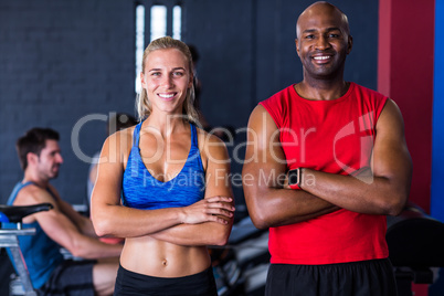 Portrait of smiling friends with arms crossed in gym