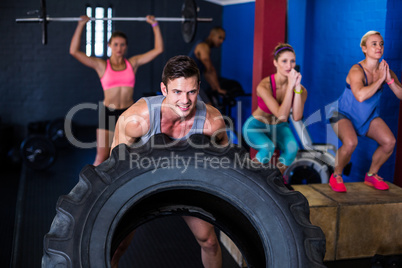 Smiling man lifting tire in gym