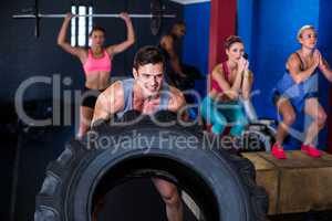 Smiling man lifting tire in gym