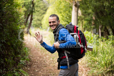 Male hiker waving hand while walking in forest