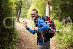 Male hiker waving hand while walking in forest