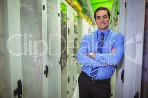 Technician standing with arms crossed in a server room