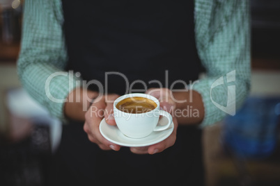 Mid section of waiter holding cup of coffee