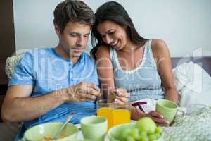 Smiling couple having breakfast on bed