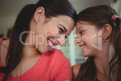 Mother and daughter looking face to face and smiling