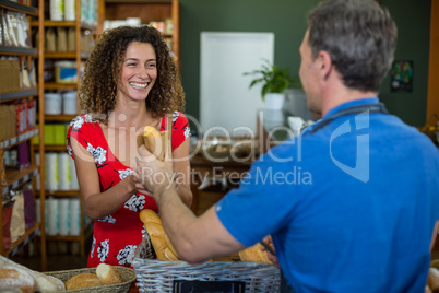 Male staff giving packed bread to woman