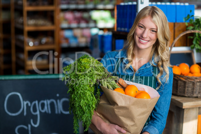 Portrait of smiling woman holding a grocery bag in organic section