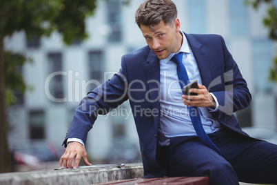 Handsome businessman holding mobile phone while using digital tablet Handsome businessman holding mobile phone while using digital tablet