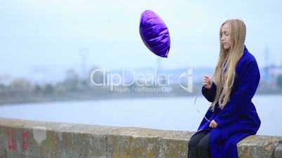 Beautiful sad blond woman with violet balloon
