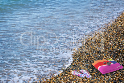 Beach shoes and a towel on the beach.