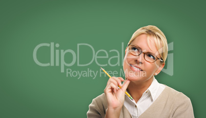 Attractive Young Woman with Pencil In Front of Blank Chalk Board