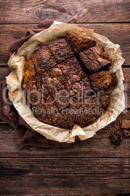 homemade chocolate brownie on dark wooden background, top view