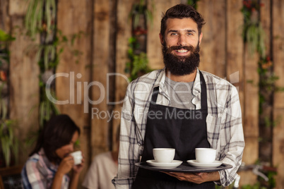 Portrait of waiter holding a cup of coffee in serving tray
