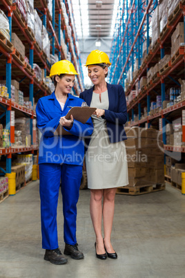 Warehouse manager and worker discussing with clipboard