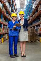 Warehouse manager and worker discussing with clipboard