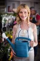 Smiling female florist holding watering can in flower shop
