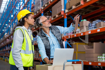 Warehouse manager and female worker interacting while using laptop