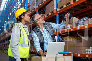 Warehouse manager and female worker interacting while using laptop