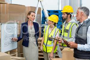 Manager and warehouse workers discussing plan on whiteboard