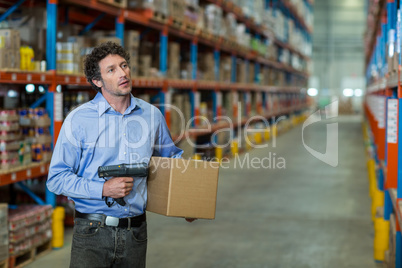 Warehouse worker holding cardboard box and barcode scanner machine