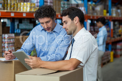 Warehouse workers discussing with digital tablet
