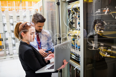 Technicians using laptop while analyzing server