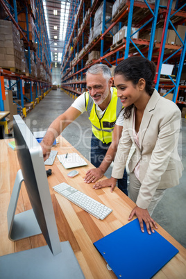 Warehouse manager and worker discussing with computer