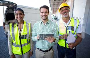 Manager and warehouse workers standing with digital tablet and clipboard