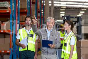 Warehouse manager and workers discussing with clipboard