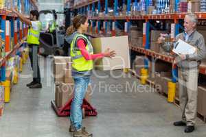 Warehouse manager showing thumbs up to female worker while carrying cardboard boxes