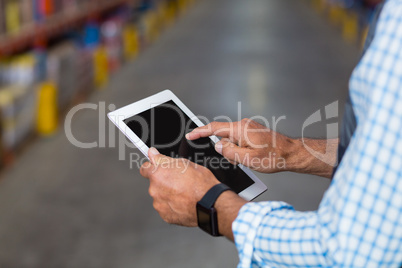 Mid section of warehouse worker using digital tablet