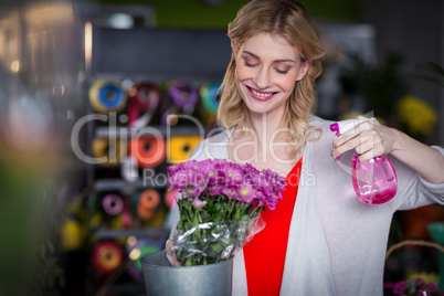 Female florist spraying water on flowers in flower shop