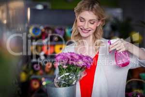 Female florist spraying water on flowers in flower shop